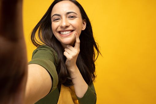 Photo of young women taking selfie on yellow background