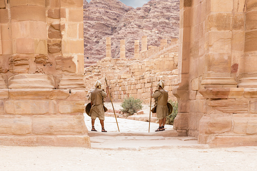 Wadi Musa, Jordan, October 05, 2023 : Two Bedouins dressed in military uniform of the ancient Nabateans guard the passage between the columns in Nabatean Kingdom of Petra in Wadi Musa city in Jordan