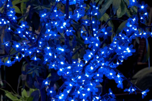 Decorative artificial glowing flowers on a branch, nighttime bright decorations.