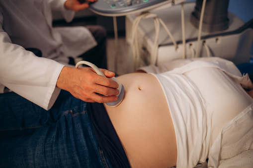 In the Hospital, Close-up Shot of the Doctor does Ultrasound Sonogram Procedure to a Pregnant Woman. Obstetrician Moving Transducer on the Belly of the Future Mother. High quality photo
