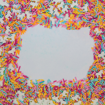 Colorful sprinkles on white paper background with space for text.