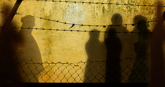 Refugee womans trapped in a camp with wires  around. Illustrated as a shadow behind the refugee fence