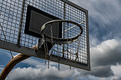 Metal Basketball Board And Ring With Chains In Front Of Sky With Heavy Clouds