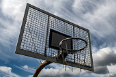Metal Basketball Board And Ring With Chains In Front Of Sky With Heavy Clouds