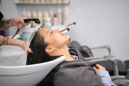 Chinese woman leaning the head on sink during a pleasurable head wash at a hair salon