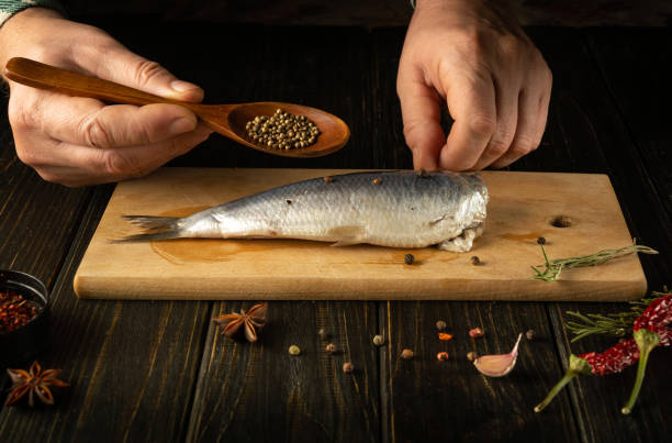 istock The chef is preparing Baltic herring fish on the kitchen table with spices and coriander for a delicious lunch. Working environment on the kitchen table 2019940948