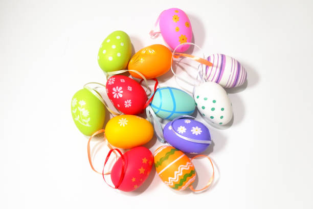 A yellow plastic Easter egg hangs from a red rope in the picture. Easter eggs as decoration. The background is dark. There is space for text.