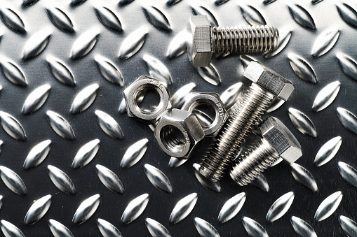Steel nuts and bolts closeup on metalic background