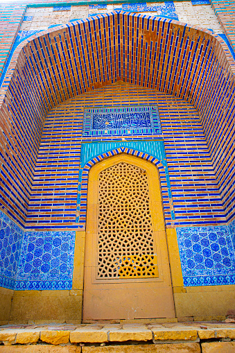 Makli Necropolis, wall with oriental ornament, blue and turquoise mosaic and arch. Beautiful funerary islamic architecture in Pakistan.