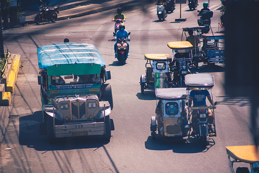 Jeepneys and tricycles plying the main street in Poblacion, San Pedro, Laguna. Many people also prefer driving motorbikes to avoid heavy traffic in this congested city. San Pedro City, Laguna, Philippines; January, 2024