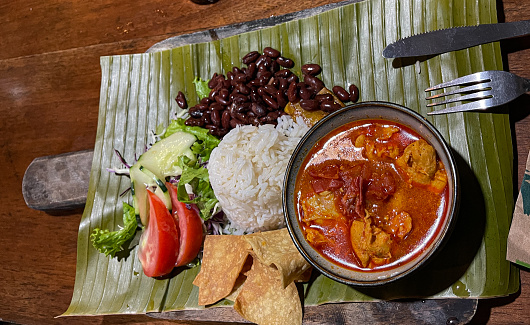 A typical Costa Rican dish known as Casado features a combination of rice, black beans, plantains, salad, a tortilla, and chicken stew for protein. It is traditionally served on a banana tree leaf in a local restaurant called a soda.