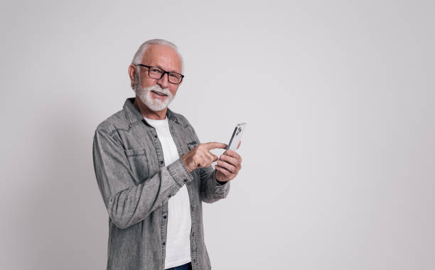 istock Smiling mature entrepreneur in eyeglasses using social media over mobile phone on white background 2020036680