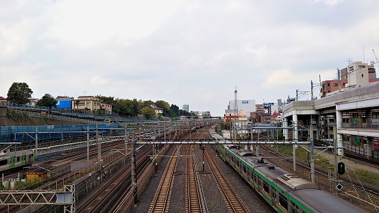 Tokyo, Japan - 10.26.2019: A train passing through a station with empty tracks alongside under a cloudy sky