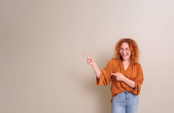 istock Cheerful young businesswoman with redhead aiming at copy space for advertisement on white background 2020046531
