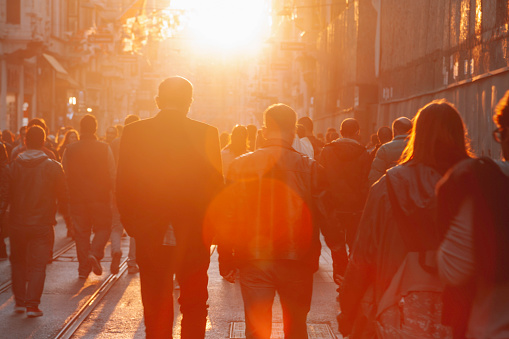 Crowded pedestrians walking on Istiklal Street on a sunny day with sun flare in Taksim, Beyoğlu, Istanbul, Turkey