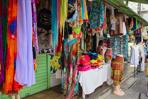 Port Louis, Mauritius - January 13, 2023: A woman stands confidently in front of a vibrant shop in the bustling Souvenir Market of Mauritius.