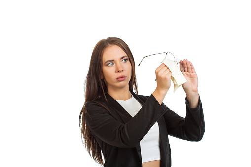 A business lady in a black jacket is wiping her glasses. Isolated on white background.