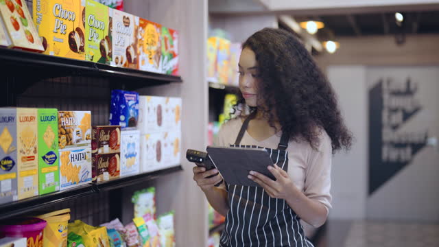 Young woman works in supermarket using barcode scanner checking products stock on shelf.