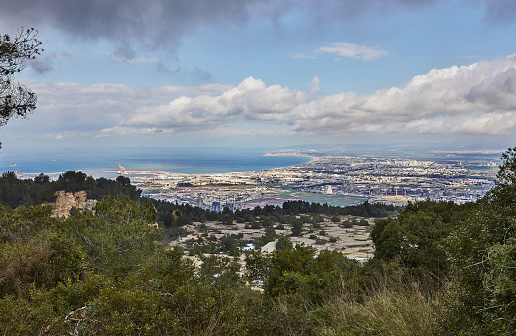 A breathtaking panoramic view of haifa as seen from mount carmel, showcasing the city's sprawling residential areas and the bustling sea port under a clear blue sky.