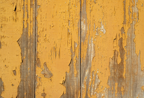 Abstract yellow, painted wall with gouges, scratches and prominent brush strokes.