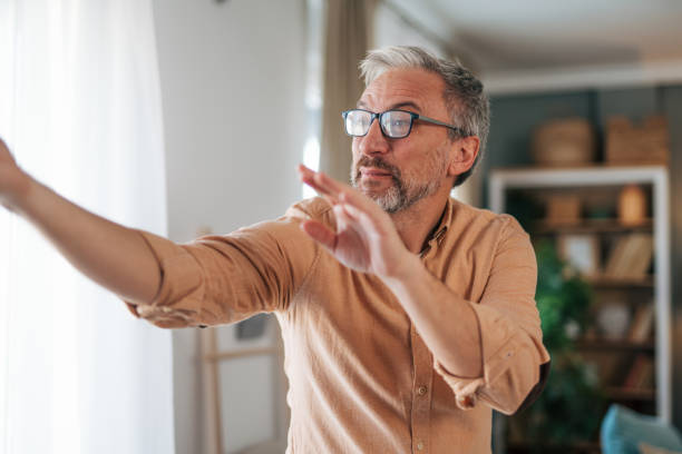 istock Mature man standing by the window and showing at something 2020152211