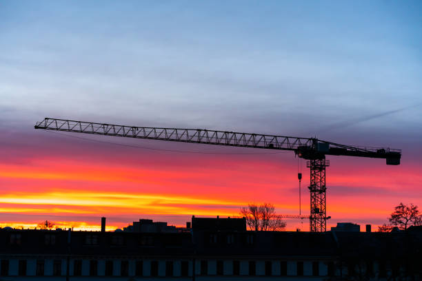 construction crane at sunrise. gradient from red to blue. Full length crane boom.