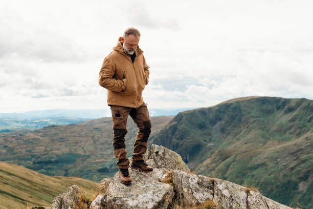 bearded man reaching the destination and on the top of mountain at sunset on autumn day travel lifestyle concept the national park lake district in england - english lake district orienteering hiking mountain стоковые фото и изображения