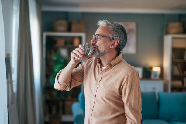 istock Middle age man standing by the window and drinkig water 2020168018