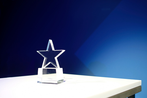 Star-shaped award made of glass on a white table with a spotlight on it