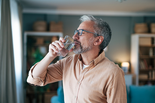 Side view of mature man standing and drinkig water.