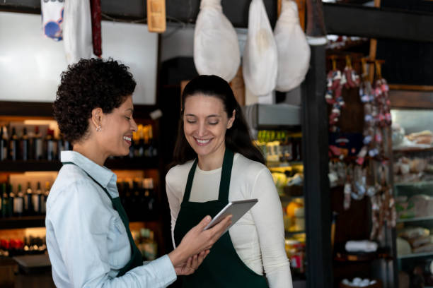 istock Diverse saleswoman checking something on tablet while talking very cheerfully at a charcuterie 2020172244