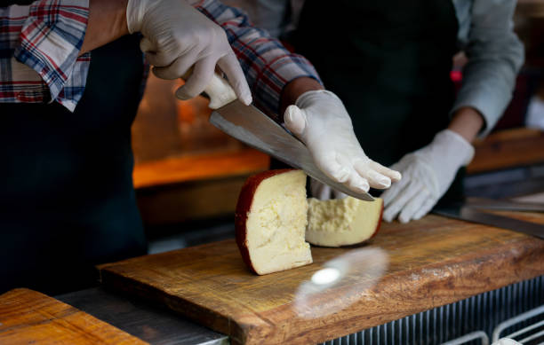 istock Owner of a deli teaching a new hire how to cut cheese properly 2020172370