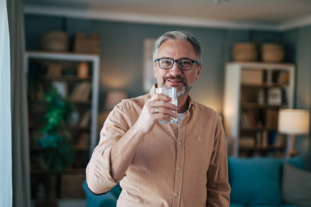 istock Man looking at camera holding glass of water 2020172940
