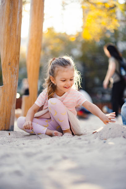 Smiling little girl sitting in the sand and having fun outdoors.