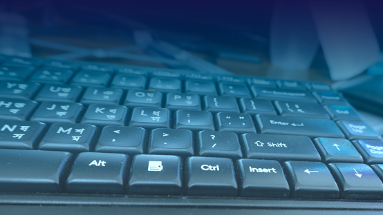 Close-up of a black computer keyboard with a blue light overlay technology background.