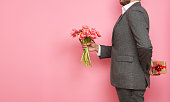 Man in suit with gift box and bouquet of tulips