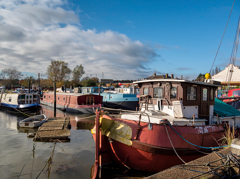 A group of houseboats moored in Woodbridge, Suffolk, Eastern England, at high tide in the River Deben.