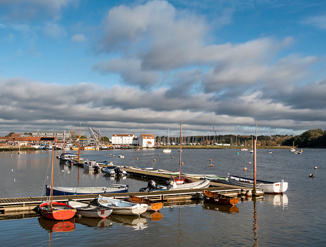 Rowing boats moored at a jetty in Woodbridge, Suffolk, Eastern England. The famous old Tide Mill is in the background.
