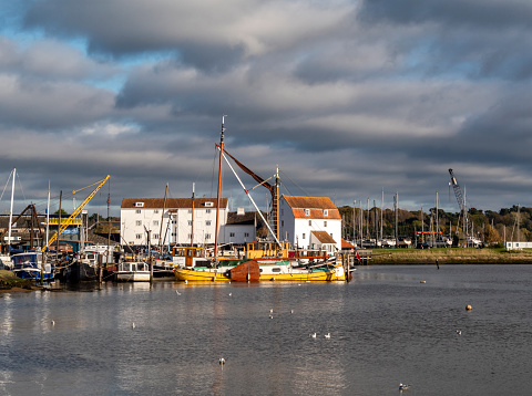 Dark clouds threatening rain hang over the historic and famous Tide Mill at Woodbridge in Suffolk, Eastern England on a sunny autumn day.