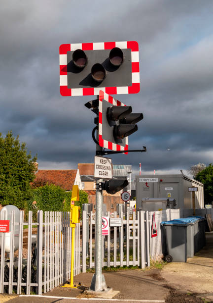 Stop-Go signals on an unmanned railway crossing near the station in Woodbridge, in Suffolk, Eastern England, on a bridge day. Dark clouds are looming, however, with the possibility of rain.