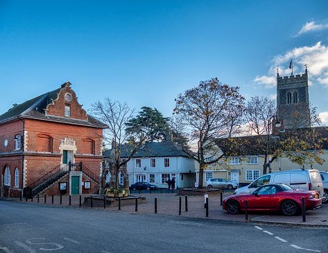 Market Hill in Woodbridge, Suffolk, Eastern England, with the Shire Hall, town water pump and St Mary the Virgin church, late on an autumn afternoon.