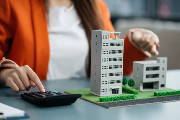 istock Home loan officer uses a calculator with a house plan. 2020240175