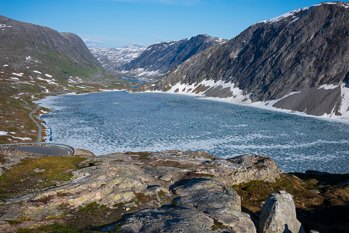 The snow capped Breiddalen Valley at Jotunheimen National Park in Norway, along the route to Geiranger, during a summer day. Aerial view of a frozen lake.