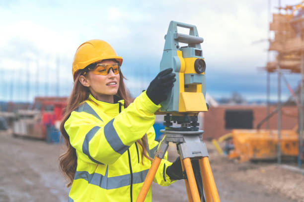female site engineer surveyor working with theodolite total station edm equipment on a building construction site outdoors - people in a row in a row business office worker zdjęcia i obrazy z banku zdjęć