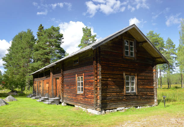 A small log cabin nestled between a snow covered field and the river Rauma in Romsdalen, Norway.