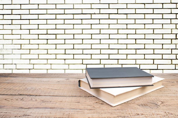 istock open book. Composition with hardback books, fanned pages on wooden deck table and Brick wall background. Books stacking. Back to school. Copy Space. Education background. 2020287387
