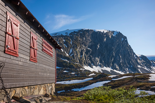 Woman walking against camera by fjord and cabins by Lovatnet/Raksetra, Norway.