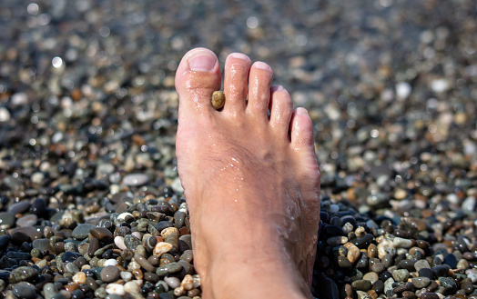 Man's foot on a pebble beach.