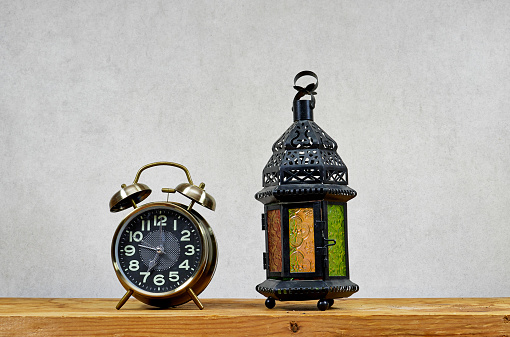 alarm clock with lantern on wooden table , ramadan concept