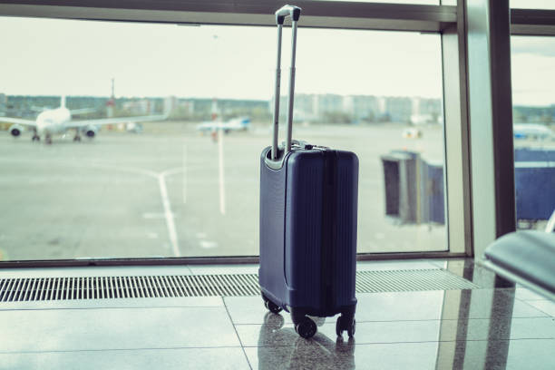 istock Suitcase in the airport terminal, by the window 2020386908